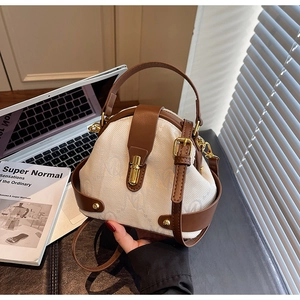 Detail of vintage canvas and brown leather handbag with gold twist lock on office desk