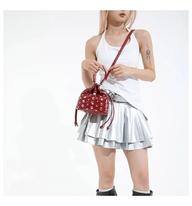 Detail of red bucket bag with silver studs, shiny finish, and drawstring chain strap