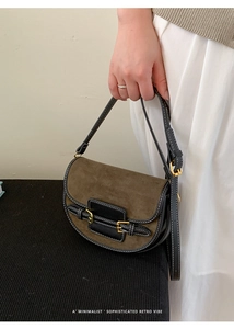 Detail of retro saddle bag featuring brown suede with black leather piping and gold buckle