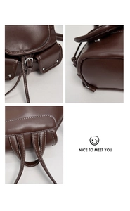 Detail of dark brown leather backpack showing drawstring closure and lychee texture