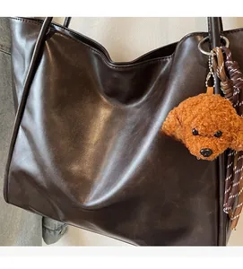 Close-up of deep brown leather tote bag with glossy texture and plush dog charm