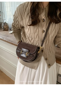 Detalle de bolso silla de montar retro marrón oscuro con gamuza y hebillas doradas