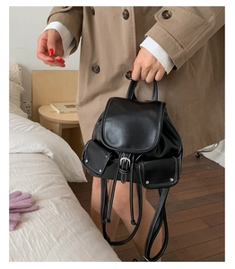 Detail view of a black leather vintage backpack featuring white contrast stitching accents