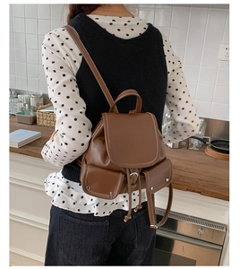 Detail of vintage brown leather backpack with white stitching and drawstring closure