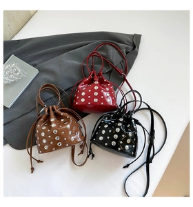 Close-up of three studded bucket bags in brown, red and black patent leather with drawstrings