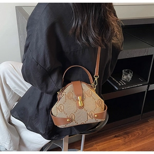 Detail of vintage brown leather handbag with MK pattern and gold metallic clasp closure