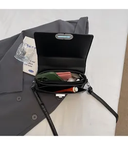 Vue intérieure d'un sac bandoulière en cuir noir avec deux compartiments et poche zippée