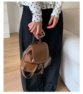 Detailed view of a brown leather mini backpack with white stitching and stylish side pockets