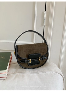 Close-up of retro brown saddle bag with suede stitching and golden metal buckle details