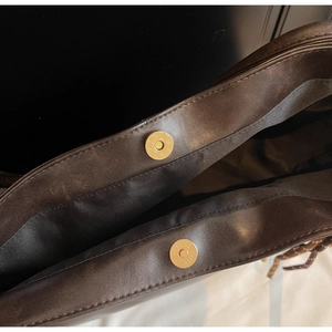 Detail of magnetic cylinder clasps and black lining on a dark brown vintage tote bag