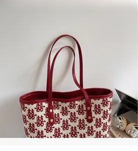 Détail du cabas de mariage rouge avec jacquard Xi et bandoulières en cuir rouge