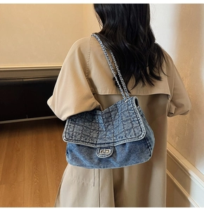 Detail of denim shoulder bag with quilted diamond pattern and metal chain strap on model