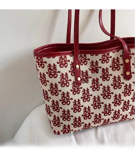 Détail du motif jacquard Xi rouge sur sac en toile crème avec poignée en cuir