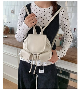 Detailed view of mini cream leather backpack with drawstring closure and metal buckles