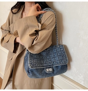 Detailed macro view of quilted blue denim texture and silver chain strap on bag