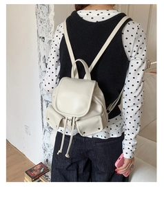 Detail of off-white PU leather backpack featuring drawstring closure and front buckle pockets