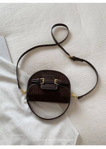 Macro detail of deep brown semi-circle saddle bag with smooth and matte leather textures