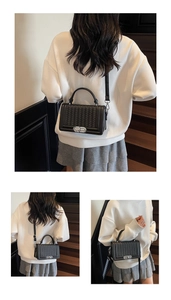 Détail du sac tressé noir avec fermoir métallique argenté et bandoulière réglable chic