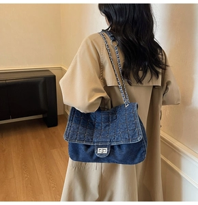 Deep blue denim chain shoulder bag with quilted pattern shown on a beige trench coat