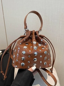 Brown bucket bag with silver studs, shiny finish, drawstring closure, and chain strap