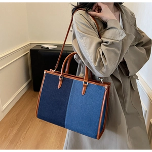 Chic patchwork denim tote bag shown worn with a trench coat for a stylish commuter look