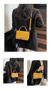 Détail d'un sac bandoulière en cuir tressé jaune avec fermoir métallique argenté
