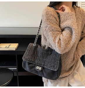 Detail of grey denim chain shoulder bag featuring quilted stitching and silver twist lock