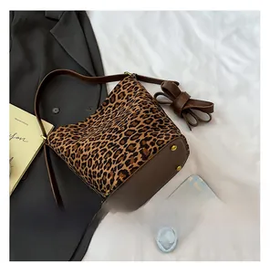 Detail showing leopard bucket bag with brown leather straps and gold protective feet