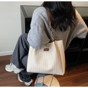 Chic beige woven tote bag with dark brown leather straps and gold metal chain accents