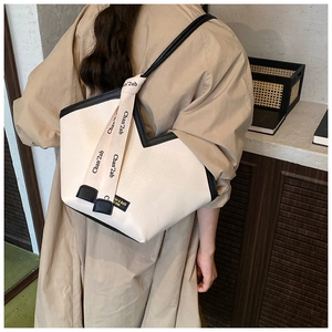 Detail of vintage beige tote bag with black piping and branded woven straps on model