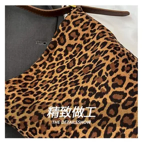 Close-up of leopard print suede bucket bag showing leather strap and gold metal buckle