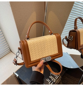 Détail du fermoir pivotant en métal et panneau tissé sur sac bandoulière en cuir marron