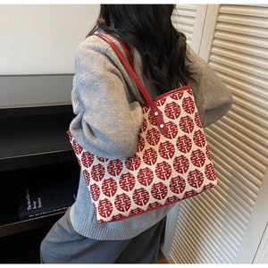 Détail du sac cabas en toile à motif Xi rouge avec bandoulière en cuir sur un modèle