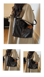 Detail of a deep brown leather tote bag with a cute teddy bear plush charm accessory