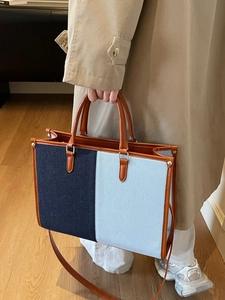 Fashionable color-block denim tote bag with leather handles shown in a lifestyle setting