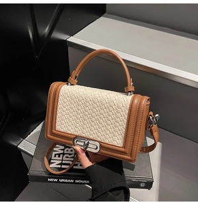 Détail d'un petit sac carré tissé avec bordure en cuir marron et fermoir rotatif argent