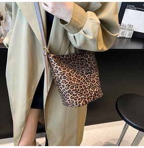 Close-up of leopard print suede bucket bag with leather strap on a model outfit