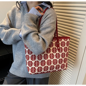Détail du tissu jacquard rouge Double Bonheur et des anses en cuir d'un sac cabas