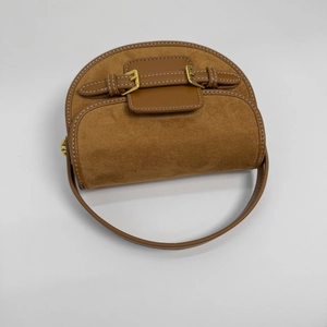 Brown suede and leather saddle bag with gold buckles and white stitching on white background