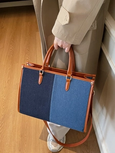 Fashionable two-tone denim tote bag with brown leather handles and adjustable straps