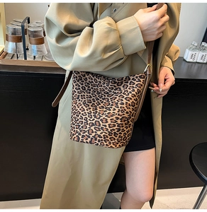 Detail of leopard print suede bucket bag showing adjustable brown strap and texture