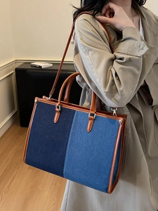 Fashionable contrast color denim tote bag with brown leather handles and shoulder strap