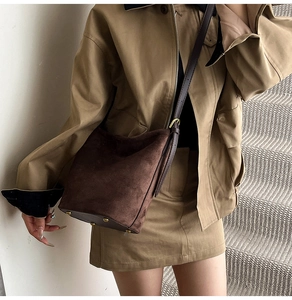 Detail of dark brown suede bucket bag featuring protective gold metal feet and leather strap