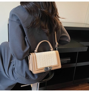 Détail du rabat tissé et du fermoir rotatif argenté sur ce sac à bandoulière élégant