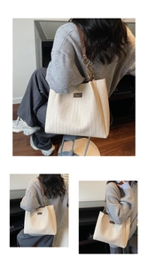 Detail of cream woven tote bag featuring leather straps and elegant gold chain accents