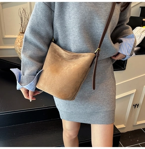 Macro shot of retro camel suede bucket bag showing fine matte texture and leather strap