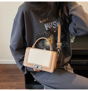 Détail du sac bandoulière tissé beige avec bordure en cuir marron et fermoir argenté
