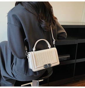 Gros plan du sac beige avec texture tressée et fermoir rotatif en métal doré élégant