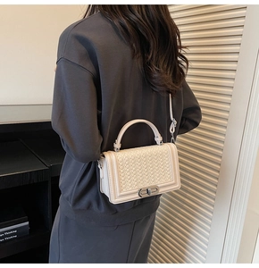 Détail d'un sac carré en cuir tressé beige avec fermoir métallique et poignée élégante