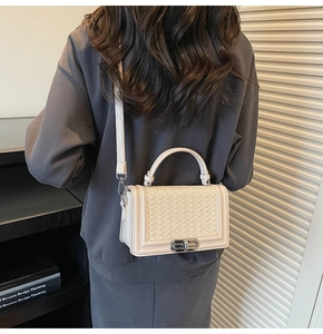 Détail du sac à bandoulière en similicuir tressé blanc avec fermoir pivotant en métal
